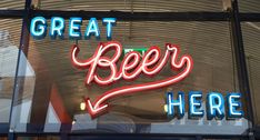 there is a neon sign that says great beer here in the window and on the wall