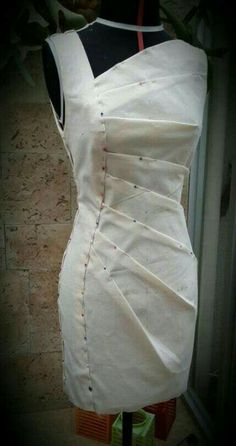 a mannequin is dressed up with white fabric and red thread on the top