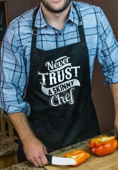 a man in an apron slicing peppers on a cutting board with a knife and fork