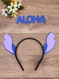 the word aloha is placed on top of a wooden table with ears and flowers