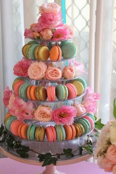 there is a tiered cake made out of macaroons and flowers on the table