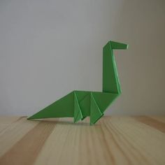 an origami green bird sitting on top of a wooden table