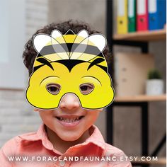 a young boy wearing a yellow mask with a black and white bee on it's face