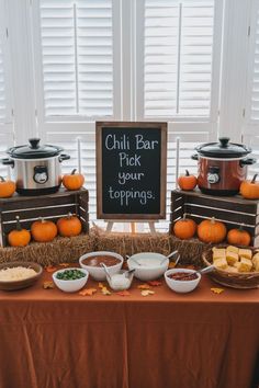 Warm and inviting chili bar setup for a November baby shower, featuring a chalkboard sign that reads 'Chili Bar, Pick your toppings,' surrounded by pumpkins and hay bales. Perfect for fall-inspired November baby shower ideas and November baby shower food options, with bowls of toppings like cheese, onions, and cornbread arranged on a rustic table. November Baby Shower Ideas, Fall Baby Shower Food, Fall Mantel Decorating Ideas, Gender Reveal Food, Lil Pumpkin Baby Shower, November Baby Shower, Pumpkin Gender Reveal