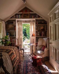 a bedroom with a bed, chair and bookshelf in the corner next to an open door