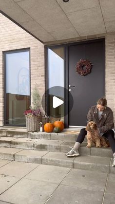 a woman sitting on the steps with her dog and pumpkins in front of her