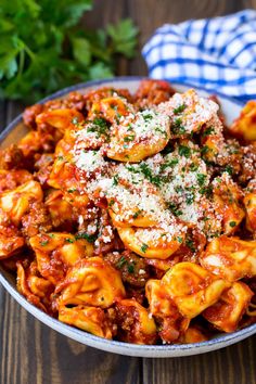 a bowl filled with pasta covered in sauce and parmesan cheese, on top of a wooden table