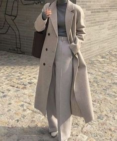 a woman standing in front of a brick wall holding an umbrella and talking on the phone