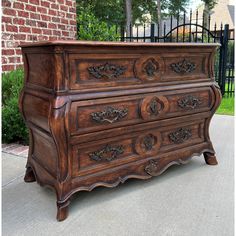 an old wooden dresser sitting on the sidewalk