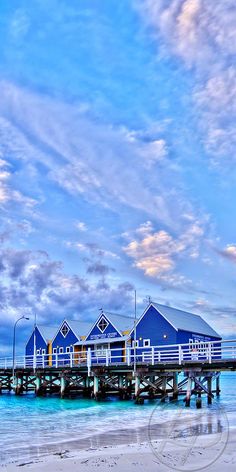 a pier that has some blue buildings on top of it in the sand and water