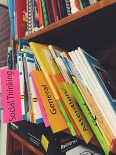 several books are stacked on top of each other in front of a book shelf full of books