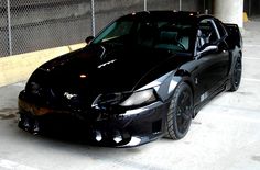 a black sports car parked in front of a fence