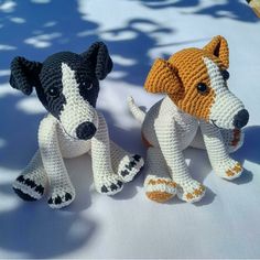 two crocheted dogs sitting next to each other on a white tablecloth covered surface