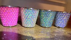 four different colored tumblers sitting on top of a wooden table next to each other