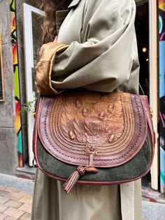 Prices for a limited edition Loewe vintage bag from the "Caza Cordobán" collection, model TOLEDO Nº 461, made of green and brown leather and suede. The flap to close the bag has a beautiful decoration of leaves and arabesques and the stitching is yellow. Large, oval, carriel-type design, with a long leather handle to hang on the shoulder and three pockets. The closure is with leather appliqués. It has a patch with the brand's logo on the side in brown leather. It has gold appliqués in stainless Green Vintage Satchel For Travel, Vintage Green Leather Satchel, Retro Green Leather Satchel, Vintage Green Satchel Shoulder Bag, Vintage Green Leather Bag, Bohemian Green Leather Bags, Green Hand-tooled Leather Shoulder Bag, Loewe Vintage, Loewe Bag