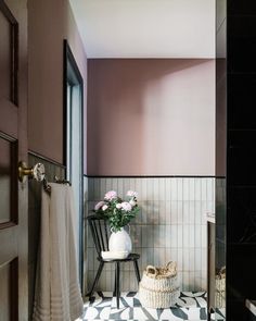 a bathroom with a checkered floor, pink walls and white towels on the rack