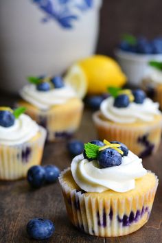 some cupcakes with blueberries and lemon on top are sitting on a table