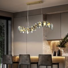 a modern chandelier hanging from the ceiling over a dining room table and chairs