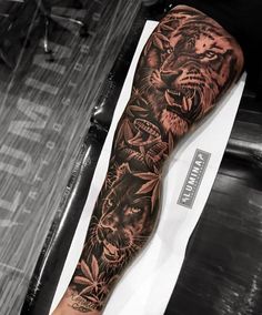 a man's arm with tattoos on it and two lions in the middle of his arm