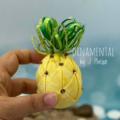 a miniature pineapple made out of fruit is being held by someone's hand