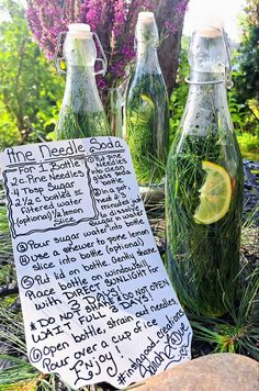 three bottles filled with green liquid sitting on top of a grass covered ground next to flowers