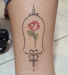 a tattoo on the leg of a woman with a rose in a bell shaped frame