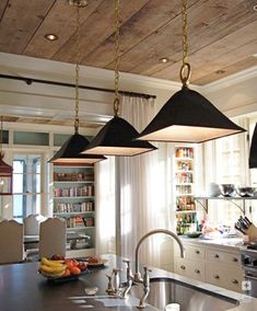 three lights hanging from the ceiling above a kitchen island in front of a stove top oven