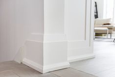 the corner of a room with white walls and wood flooring is seen in this image