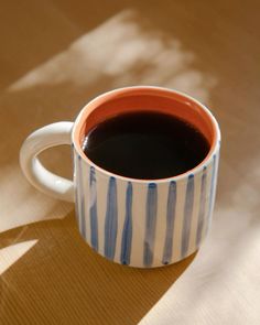 a cup of coffee sitting on top of a table next to a shadow cast by the sun