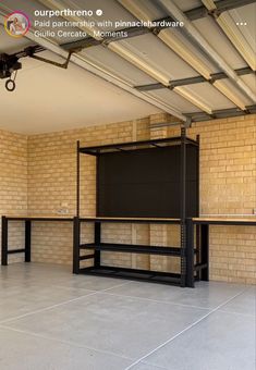 an empty room with two tables and one shelf on the floor, in front of a brick wall