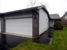 a two story house with a garage in the front yard and green grass on both sides