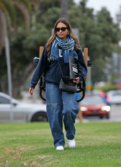 a woman walking across a grass covered field