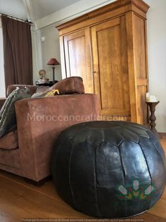 a living room with a brown leather chair and ottoman in front of a wooden cabinet