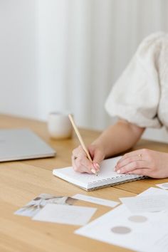 a woman writing on a notebook with a pencil