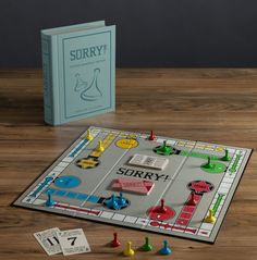 a board game sitting on top of a wooden table next to a book and two pieces of paper