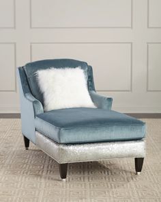 an upholstered blue chair with white pillows on the armrests in front of a paneled wall