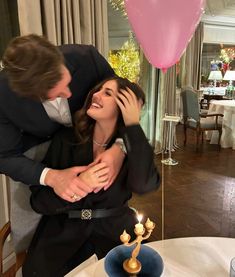 a man and woman hugging each other in front of a cake with candles on it