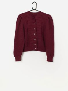 Vintage Austrian wool folk cardigan in burgundy. This beautiful burgundy red 90s cardigan features puff shoulders, a V-neck and a dainty floral button closure. Made from a mid-weight pure new wool.  Our recommended size: Small Label says: No size label Condition: Very good  Material: 100% pure new wool Measurements in inches: Pit to pit: 18 Shoulder: 14 Front length: 20 Back length: 20 Sleeve length: 23 Hem unstretched: 14 Hem stretched: 18 We recommend that you compare our measurements to a sim Fitted Burgundy Cardigan For Winter, Vintage Button Closure Sweater For Fall, Vintage Winter Cardigan With Button Closure, Classic Burgundy Winter Sweater, Fitted Burgundy Cardigan For Fall, Vintage Burgundy Outerwear For Fall, 90s Cardigan, Size Label, Vintage Wear