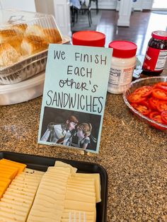 some crackers and cheese are sitting on a counter next to a sign that says we finish each other's sandwiches