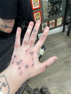 a person with tattoos on their hand is sitting in a barbershop and holding his hand up to the camera