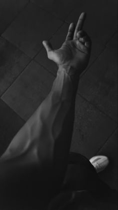 a person holding their hand up in the air while sitting on a tile floor with his foot propped up