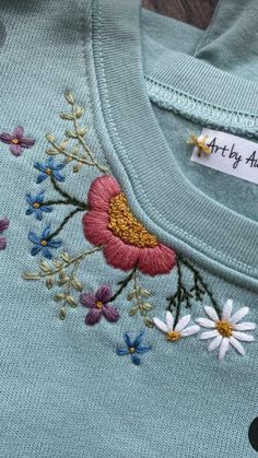 an embroidered t - shirt with daisies and flowers on the front, along with a name tag