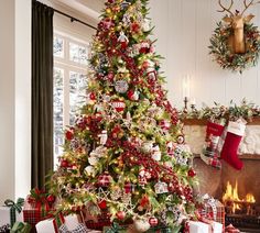 a decorated christmas tree in front of a fireplace