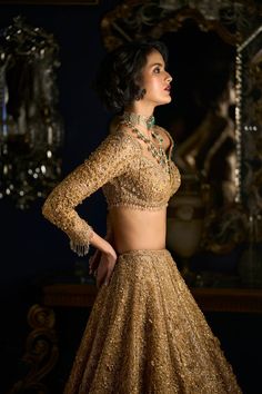 This lehenga set feature all over three-dimensional floral embroidery in gold thread. The base is covered with crystal in an intricate geometric pattern. The ensemble is paired with an embroidered full sleeves blouse shows tassels at the wrist. The heavily embroidered dupatta also has golden crystal tassels on all four sides. DELIVERY TIMEPlease allow 8-12 weeks for your outfit to arrive. FABRIC DETAILSLehenga - Net / Dupatta - Net Professional cleaning only. Golden Net Blouse Designs Latest, Net Lehenga Designs Latest, Lehenga Blouse Pattern, Golden Blouse Designs, Full Sleeves Blouse, Punjabi Dress Design, Golden Lehenga, Cancan Lehenga, Seema Gujral