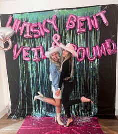 two women posing in front of a photo booth