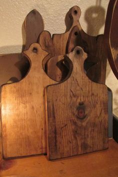 three wooden cutting boards sitting on top of a table next to a mirror and clock