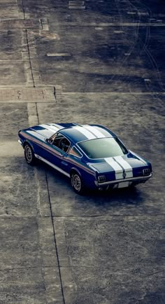 a blue and white mustang sitting on top of an airport tarmac with no one around it