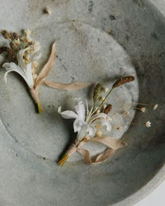 two white flowers are placed on a gray plate