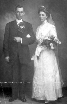 an old black and white photo of a man and woman dressed in formal wear standing next to each other