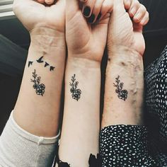 two women with matching tattoos on their arms holding each other's hands and looking at the camera